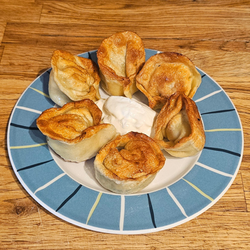 A dish of six boiled and fried dumplings with a dollop of smetana in the middle