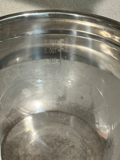Photo of a stainless steel bowl with volume markings on it where you can see a clear line at the~1.5L where the dullness ends and the polished part becomes visablr